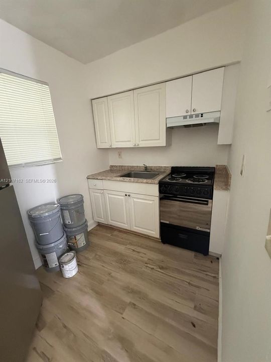 Kitchen featuring white cabinetry, stone-finish countertops, an integrated stovetop, and wood-finish flooring