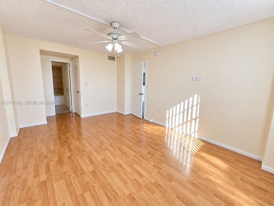 Interior space featuring wood-finish flooring, a ceiling fan with integrated lighting, and white paneled doors