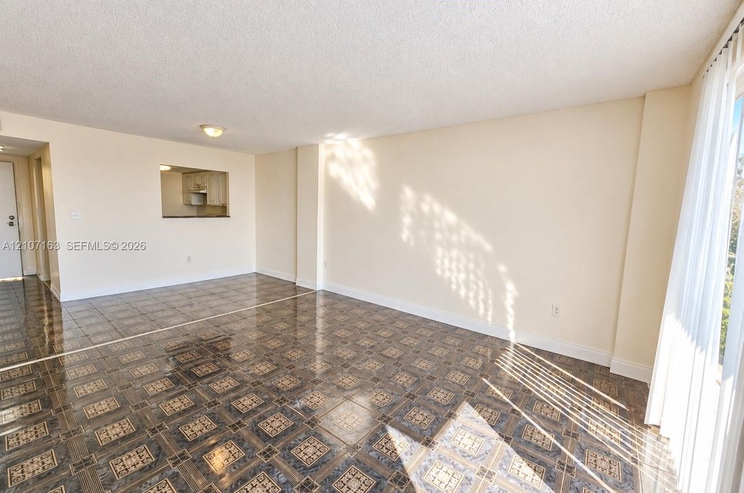 Interior space featuring patterned tile flooring, a pass-through opening, and floor-to-ceiling windows