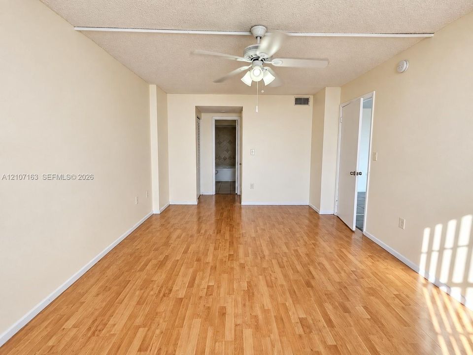 Room featuring wood-finish flooring, a central ceiling fan with integrated lighting, textured ceiling, and double-door entry