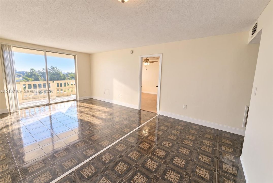 Open-concept living space featuring patterned tile flooring and glass sliding doors to a concrete balcony