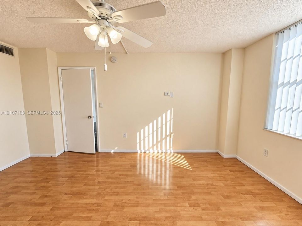 Interior space featuring wood-finish flooring, a ceiling fan with integrated lighting, and vertical window blinds