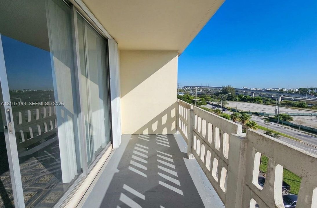 Private balcony featuring concrete flooring and geometric decorative concrete railings, accessible via full-height sliding glass doors