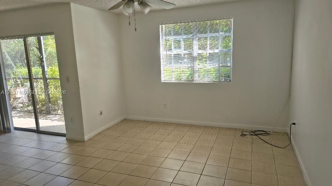 Interior space featuring tile flooring, sliding glass door, multi-pane window, and ceiling fan with light fixture