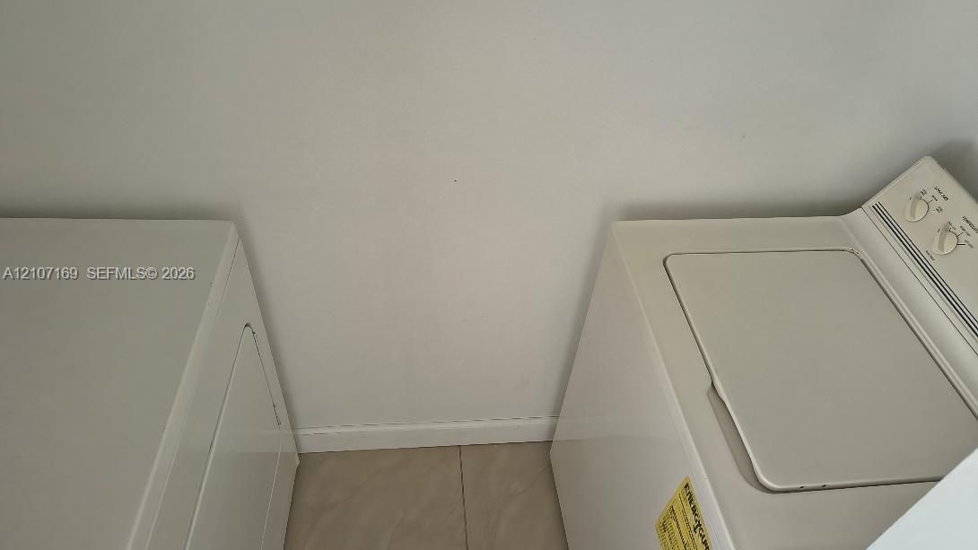 Dedicated laundry area featuring tile flooring and white wall finishes