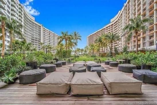Expansive wooden deck featuring mature palm trees, curated tropical landscaping, and large-scale residential architecture