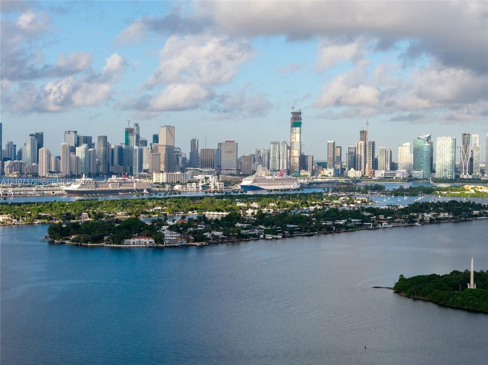 Aerial perspective featuring a metropolitan skyline, deep water bay, and waterfront island landscape