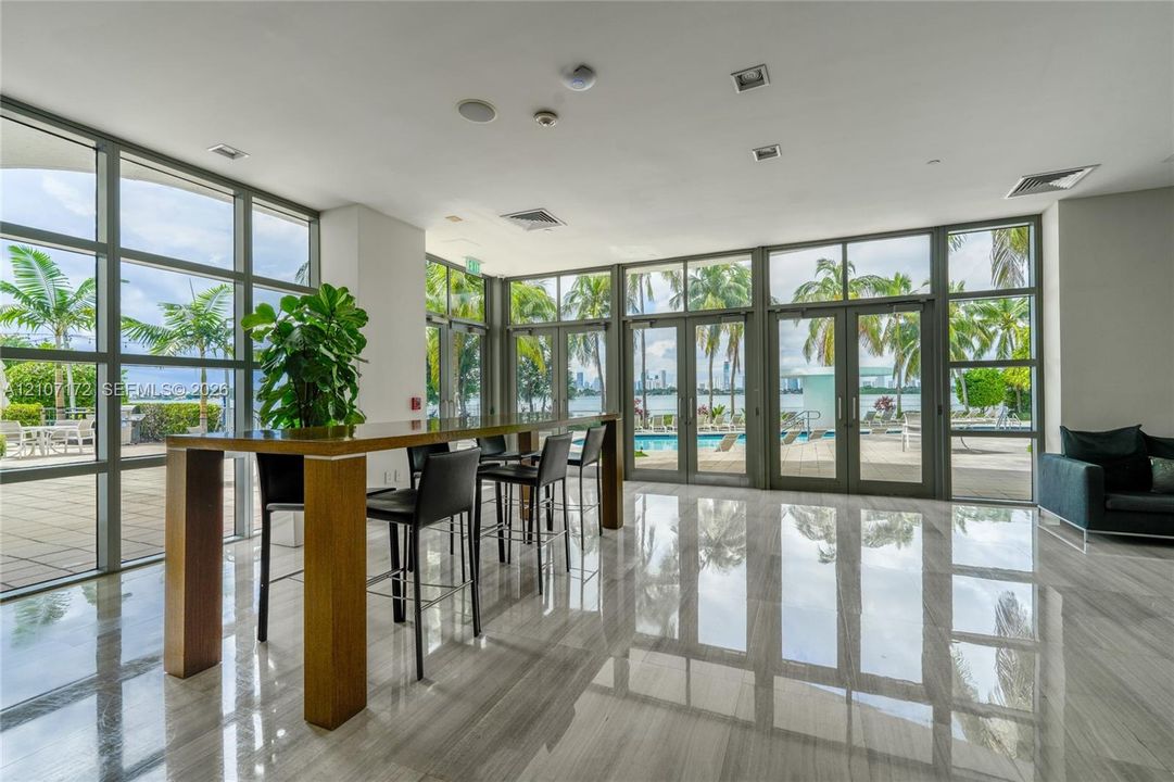 Floor-to-ceiling windows, polished stone flooring, and multiple glass-paned doors featuring metal frames