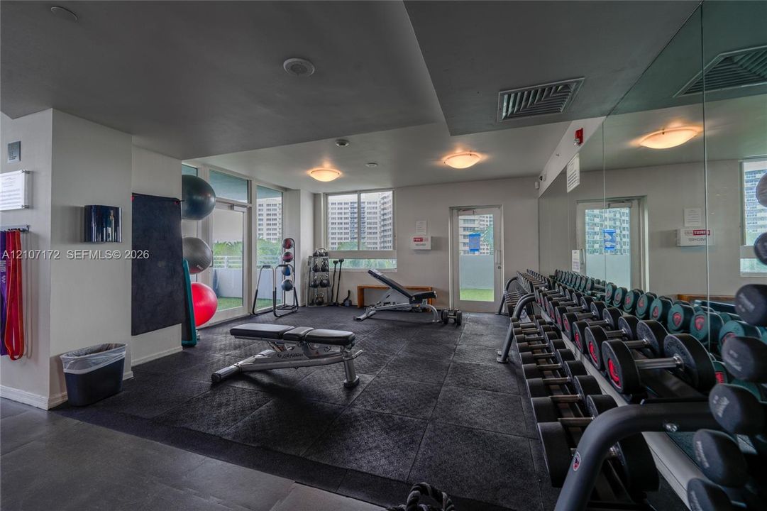 Fitness center featuring rubberized floor surfacing, full-wall mirrors, recessed lighting, and access to exterior space