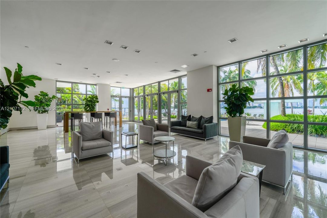 Open-concept interior featuring floor-to-ceiling glass wall panels, polished large-format tile flooring, and recessed ceiling lighting