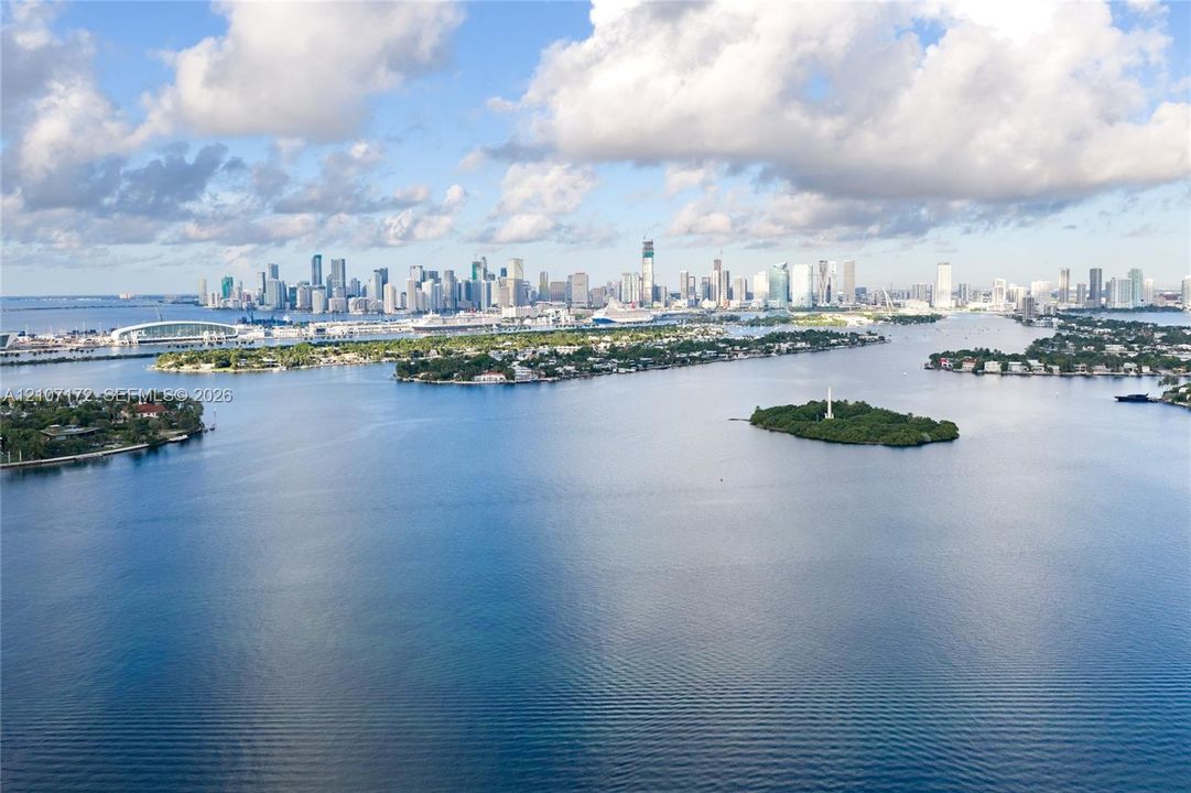 Aerial perspective featuring expansive open water, island topography, and a metropolitan skyline backdrop