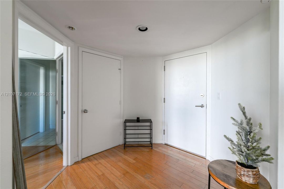 Entryway featuring wood-finish flooring, two interior doors, and recessed ceiling lighting