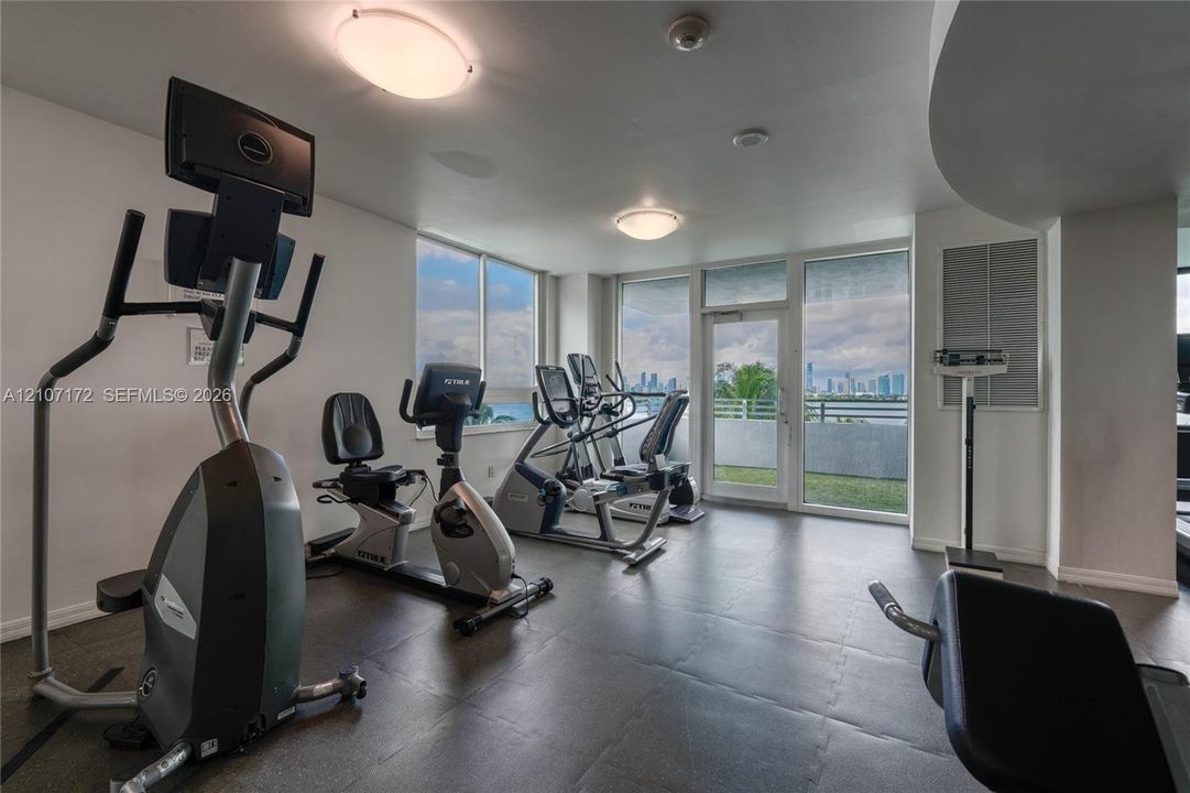 Fitness center featuring tile flooring, ceiling-mounted lighting, and floor-to-ceiling windows with access to an exterior terrace
