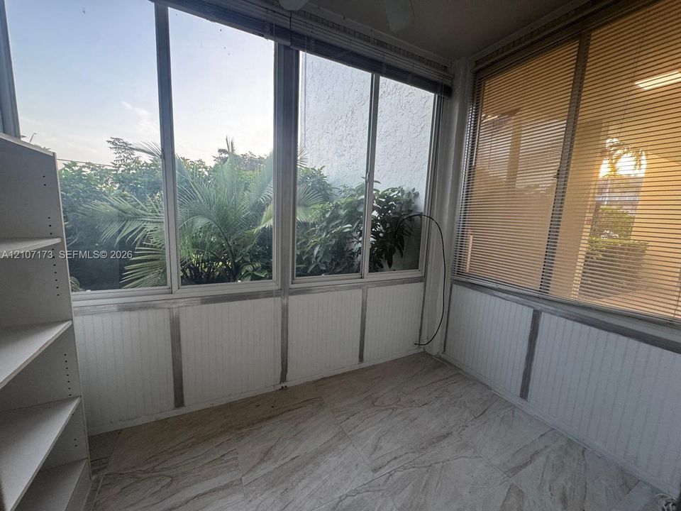 Enclosed sunroom featuring floor-to-ceiling windows, white beadboard wainscoting, and large-format tile flooring