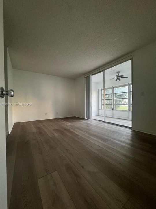 Wood-finish flooring, neutral walls, and large sliding glass doors providing external access