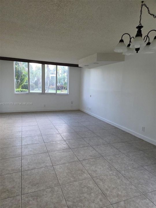 Large-format neutral floor tiling, multi-pane windows, and a multi-arm suspended light fixture