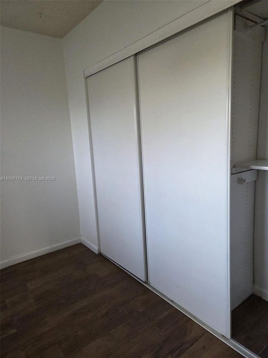 Sliding door closet featuring integrated white shelving and wood-finish flooring