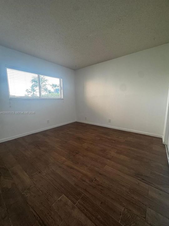 Room featuring wood-finish flooring and a horizontal window with blinds