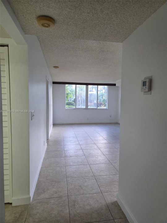 Interior space featuring large-format neutral tile flooring, expansive windows, and louvered closet doors