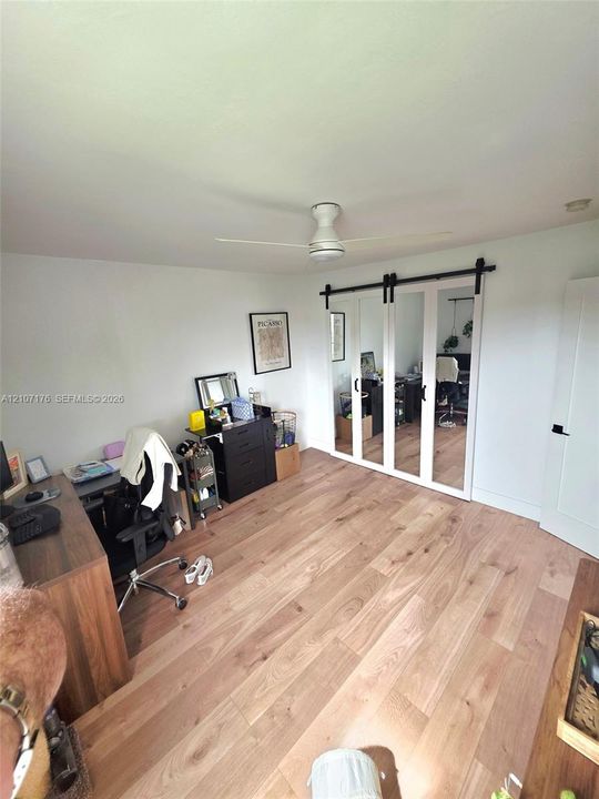 Wood-finish flooring, mirrored sliding doors with matte black hardware, and a ceiling-mounted fan
