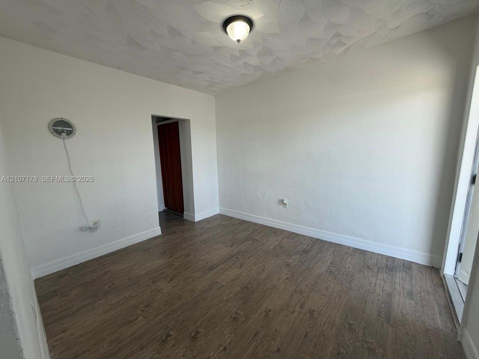 Room featuring wood-finish flooring, textured ceiling, and a central flush-mount ceiling light fixture