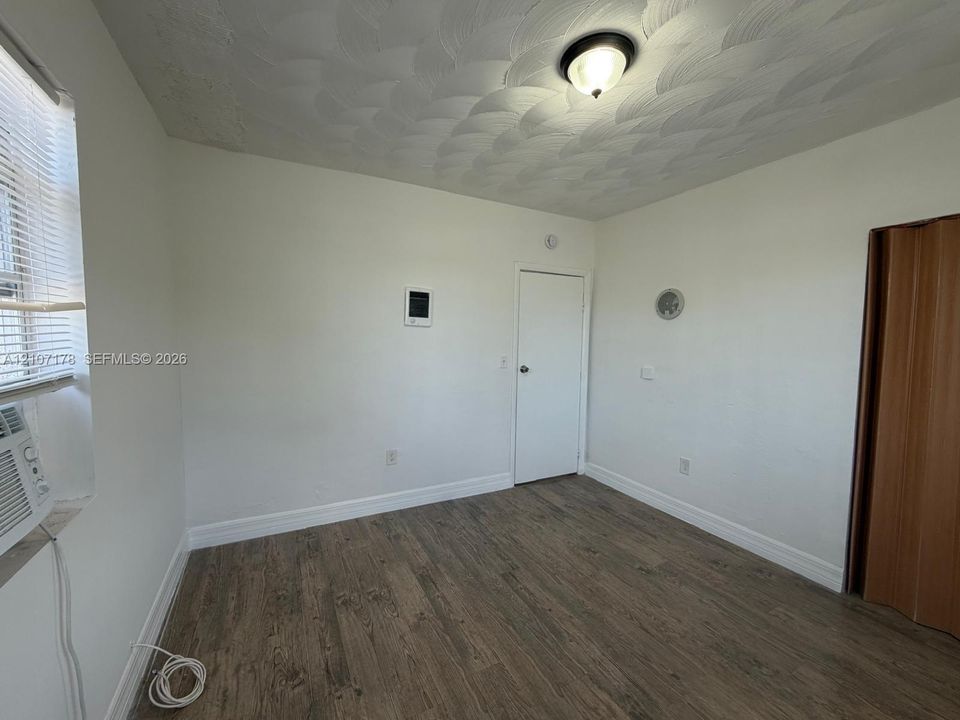 Room featuring wood-finish flooring, textured ceiling, flush-mount light fixture, and wood-finish folding door