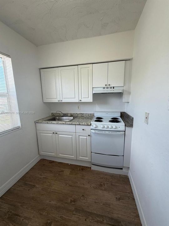 Kitchenette featuring white cabinetry, stone-patterned countertops, a stainless steel sink, a four-burner electric range, and wood-finish flooring