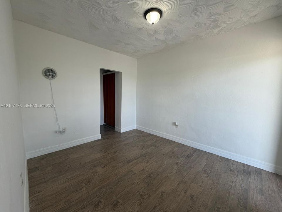 Neutral-toned walls, textured ceiling, wood-finish flooring, and semi-flush mount ceiling fixture