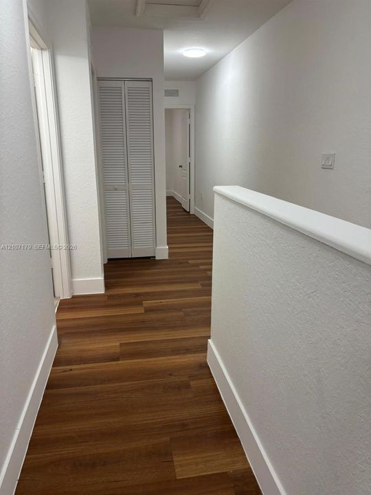 Wood-finish flooring, white louvered-style bi-fold doors, and neutral wall tones