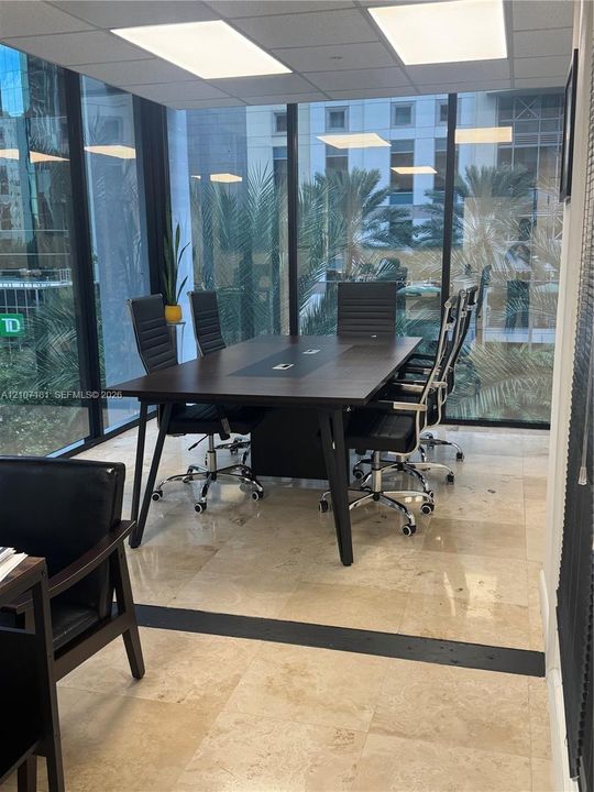 Floor-to-ceiling glass walls, polished stone flooring, recessed ceiling lighting, and integrated dark-finish built-in conference table