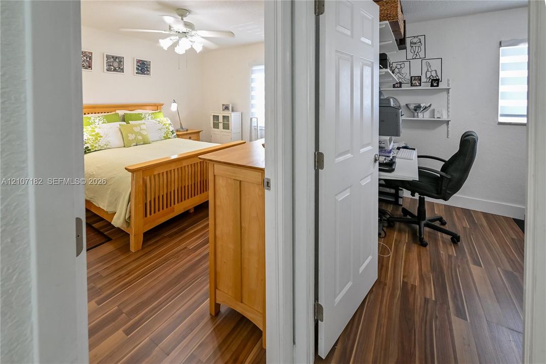 Wood-finish flooring throughout, ceiling-mounted light fixture with fan, and white paneled doors