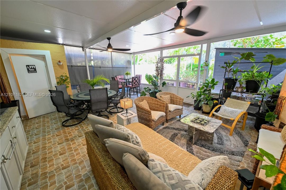 Screened-in outdoor patio featuring tile flooring, dual ceiling fans, and built-in cabinetry
