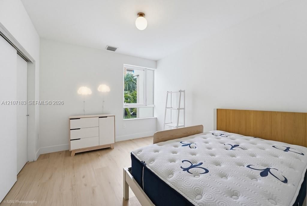 Bedroom featuring wood-finish flooring, a large window, sliding-door closet, and modern ceiling lighting