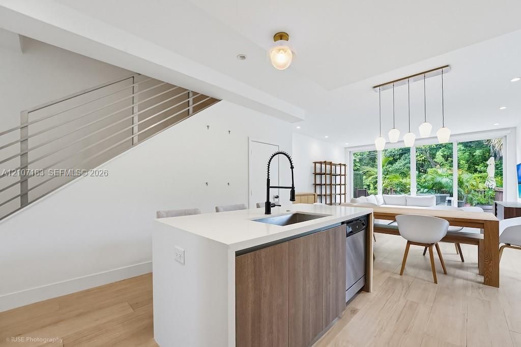 Kitchen island featuring a stone countertop, wood-finish cabinetry, and a gooseneck faucet