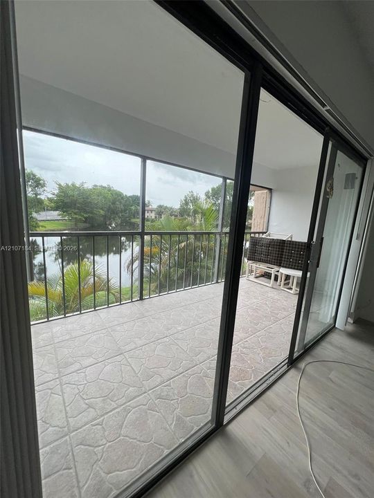Screened balcony featuring tiled flooring, a metal railing, and water frontage
