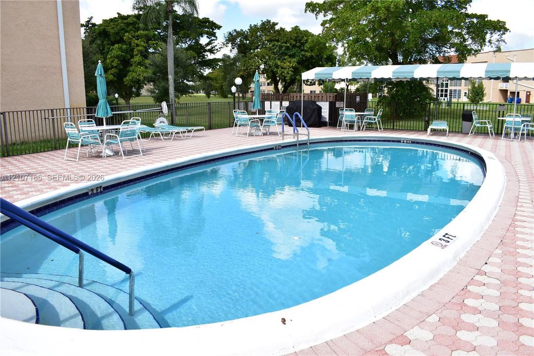 Nearby in-ground swimming pool is heated in winter and features a curved design, stepped entry, metal safety handrails, and a paved brick surround