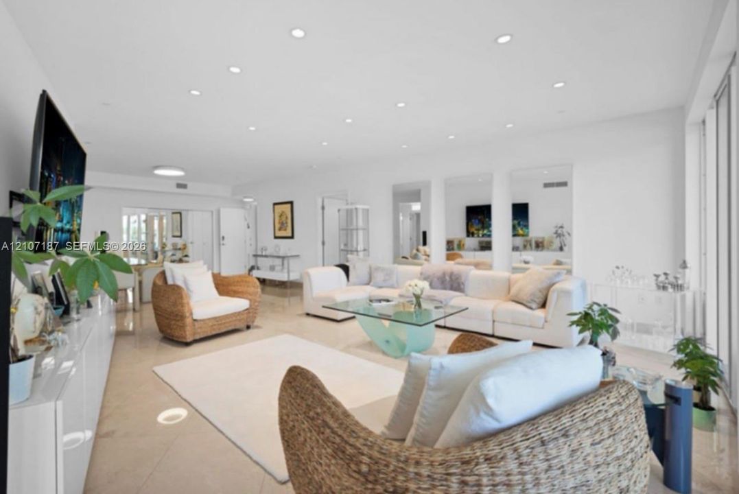 Open-concept interior featuring large-format tile flooring, recessed ceiling lighting, and three floor-to-ceiling wall mirrors