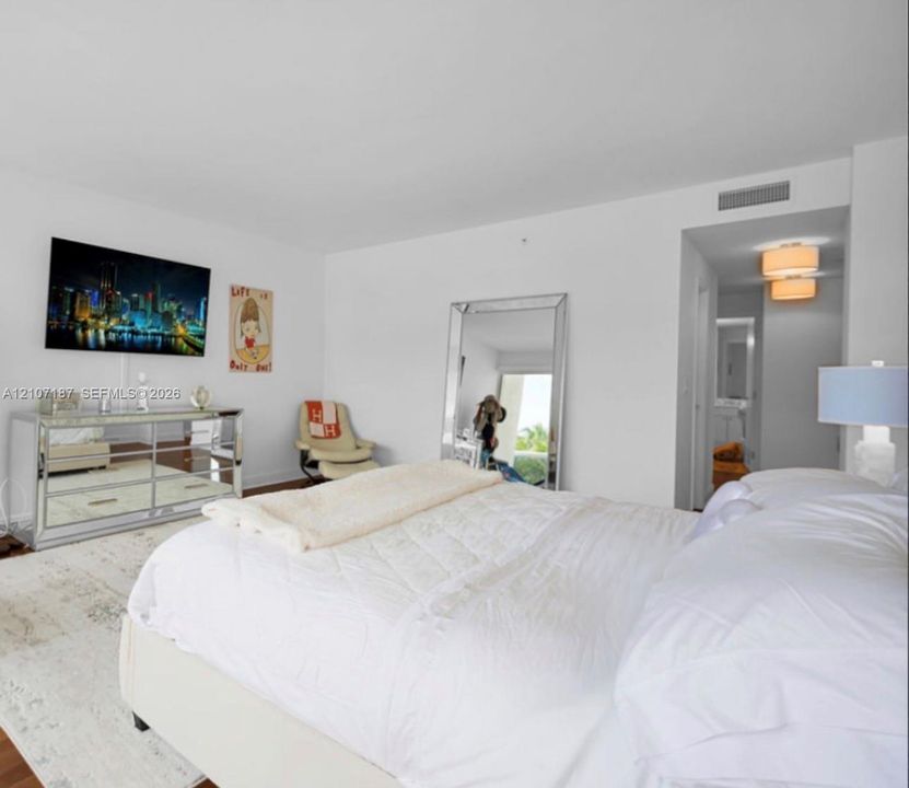 Neutral-toned interior space featuring wood-finish flooring, crisp white walls, and a recessed ceiling lighting fixture