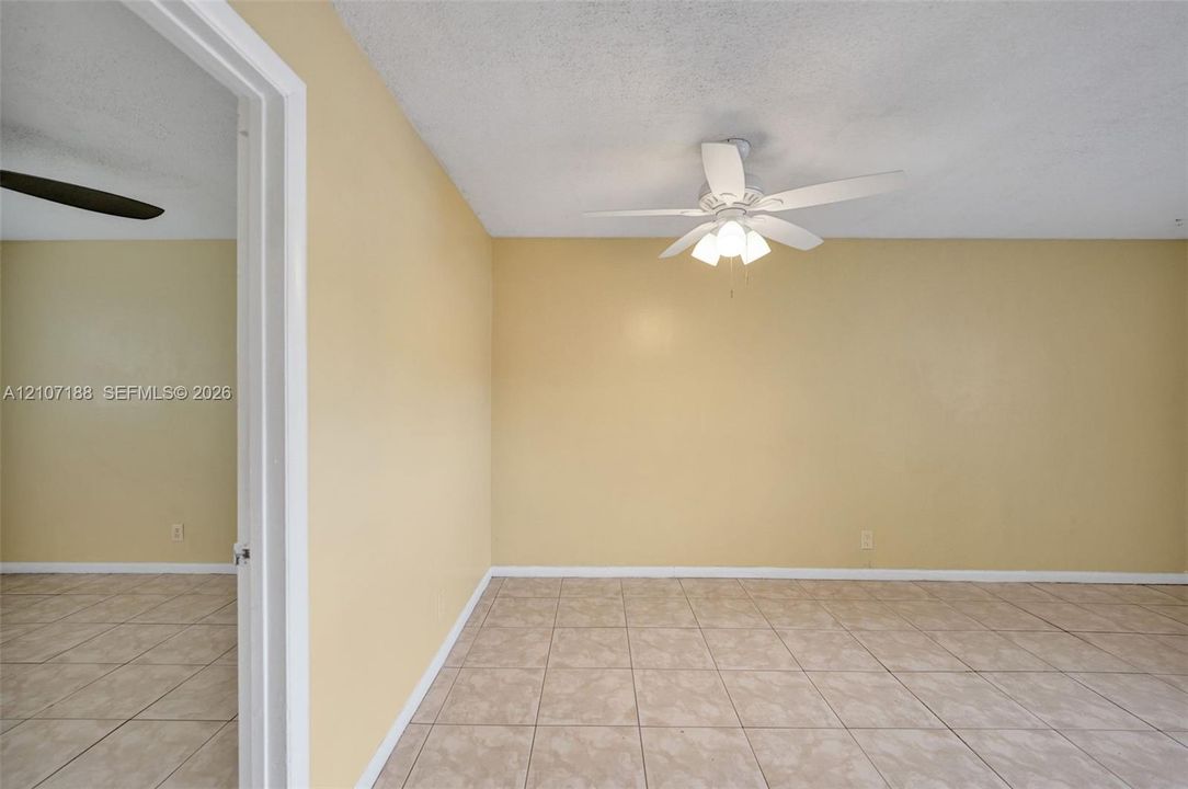 Room featuring ceramic tile flooring, a center-mounted ceiling fan with integrated lighting, and a white door frame
