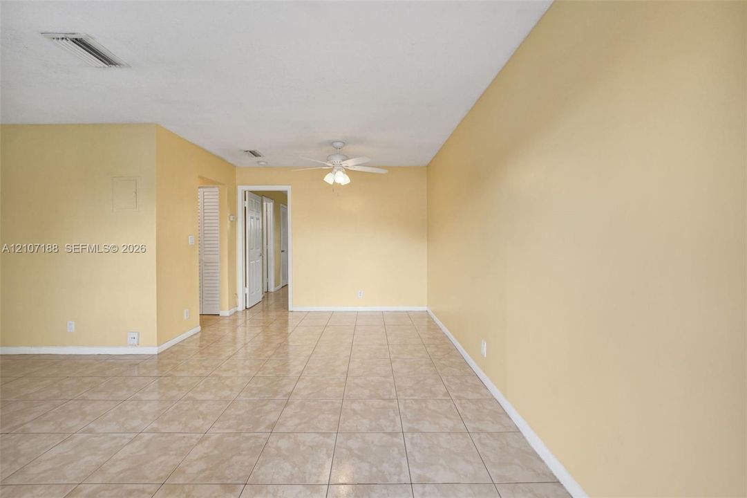 Interior space featuring neutral-toned walls, tile flooring, and a ceiling fan with integrated lighting