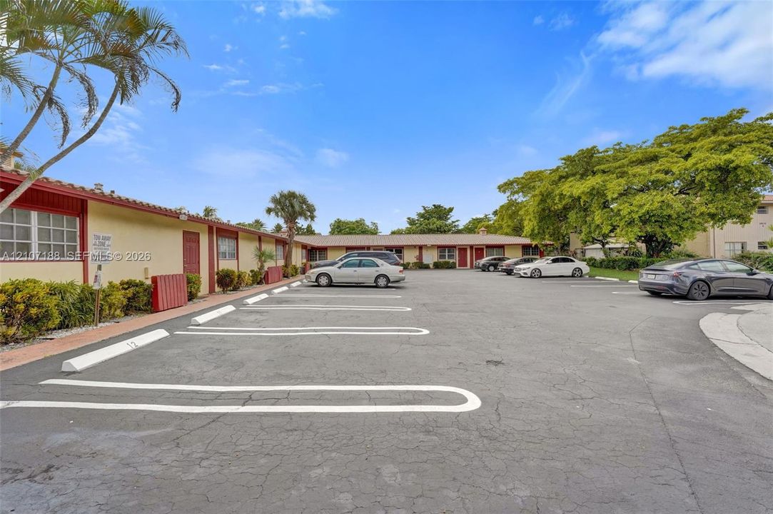 Single-story exterior featuring a tile roof, dedicated parking spaces, and mature landscaping