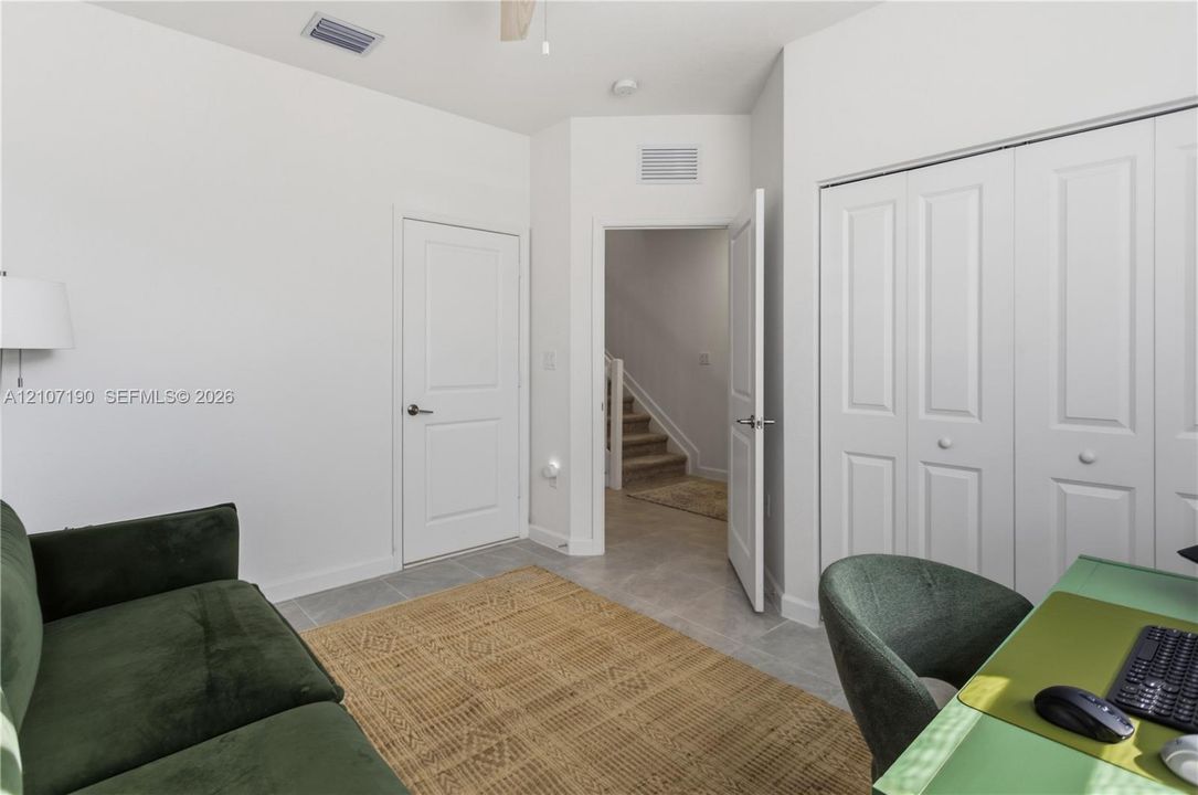 Neutral interior featuring light-toned tile flooring, white paneled doors, and a double-door closet with white trim