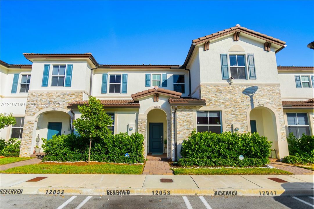Multi-story exterior featuring a stone veneer facade, stucco siding, a tiled roof, decorative window shutters, and a covered entryway
