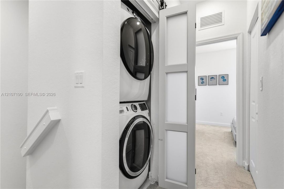 Laundry area featuring a stacked washer and dryer unit enclosed by a sliding barn-style door with frosted glass panels