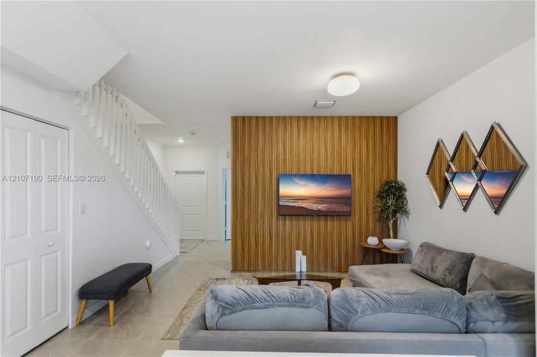 Interior space featuring a wood-slat accent wall, tile flooring, and a white staircase with a wooden handrail