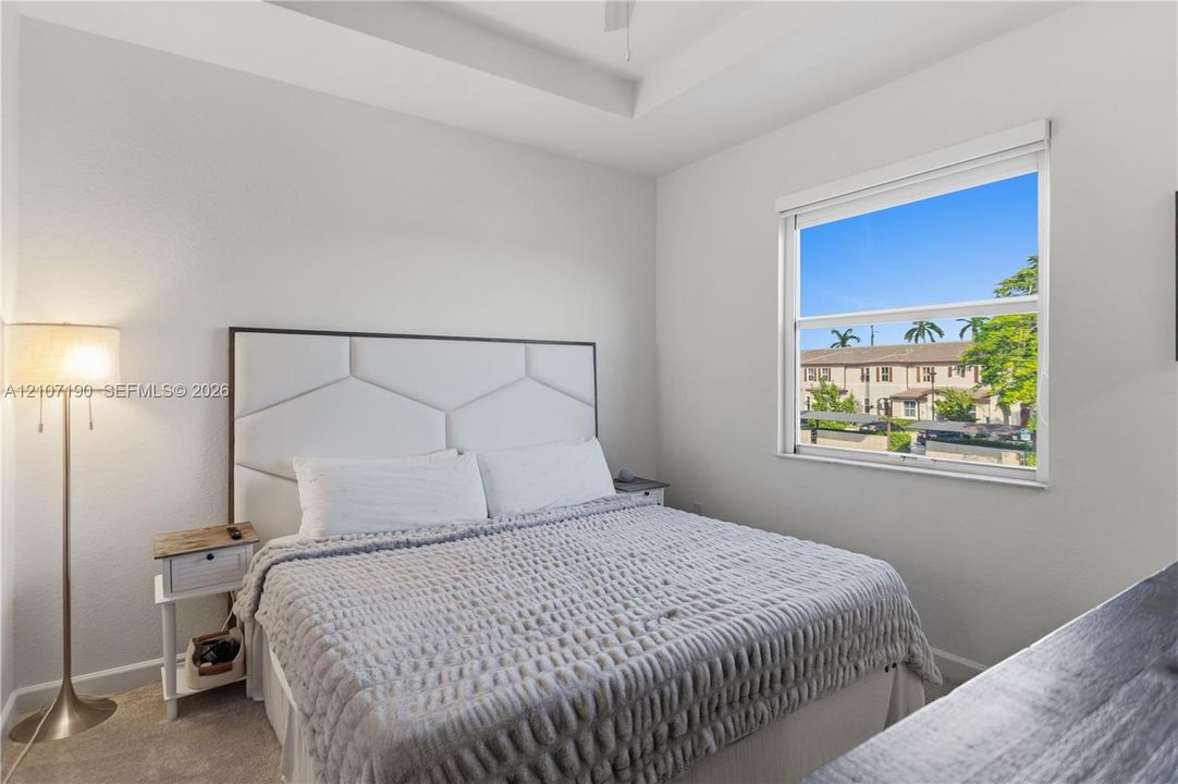 Neutral-toned room featuring a tray ceiling, ceiling fan, and a large single-hung window