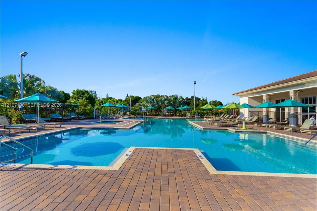 Swimming pool featuring a paver deck, integrated lap lanes, shallow sun shelf, and metal handrails