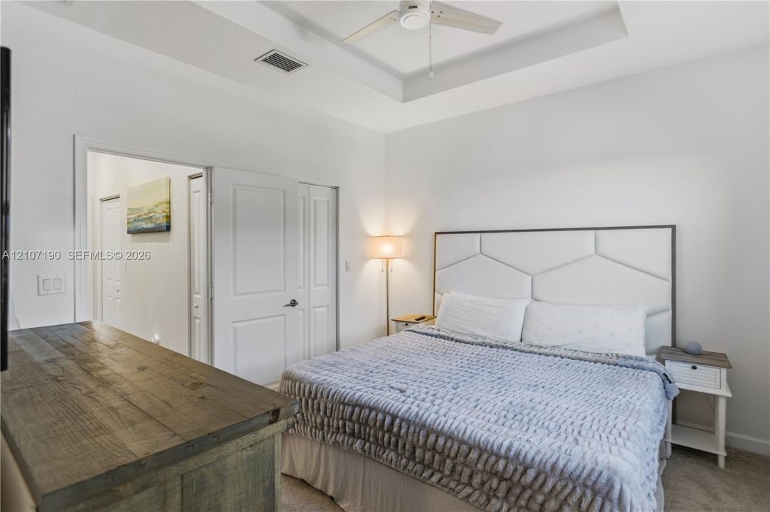 Tray ceiling with integrated ceiling fan, carpeted flooring, and multi-panel interior doors