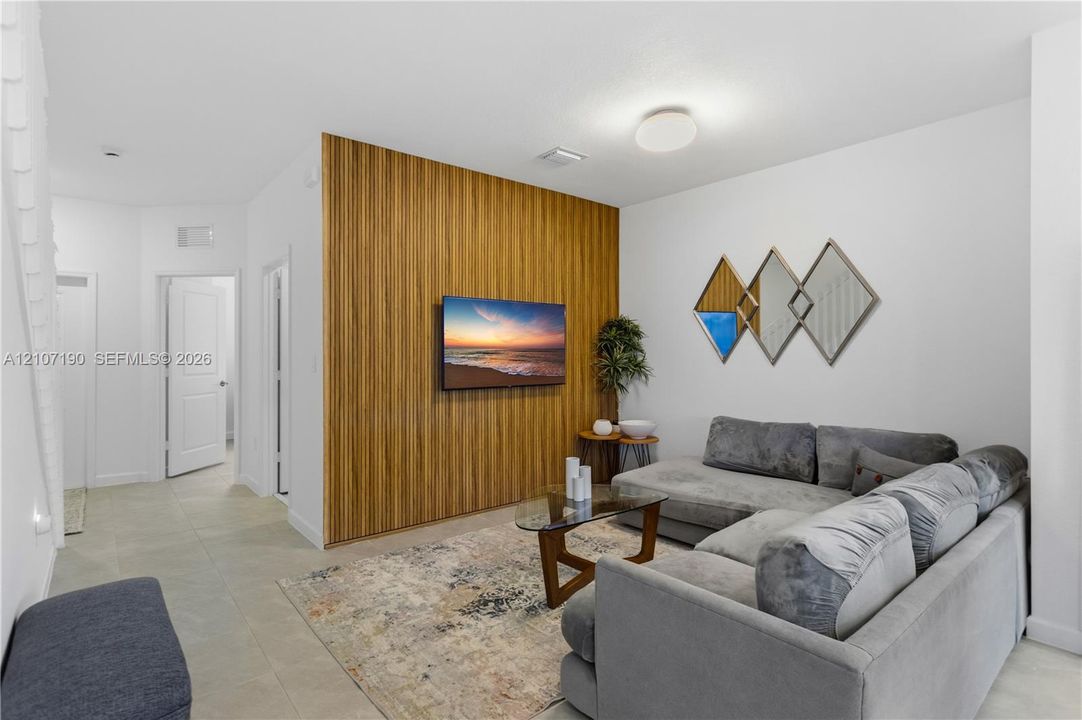 Interior space featuring a floor-to-ceiling wood-slat accent wall, neutral large-format tile flooring, and a low-profile flush-mount ceiling light fixture