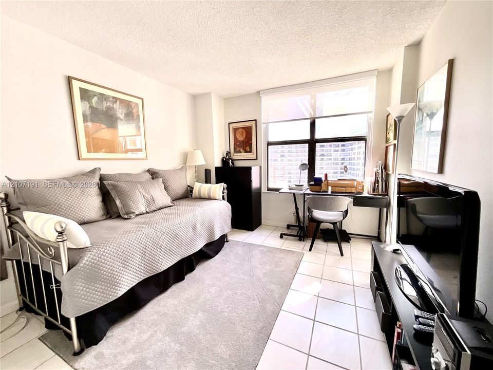 Light-filled room featuring large, multi-pane windows with integrated shades and neutral-toned floor tiling